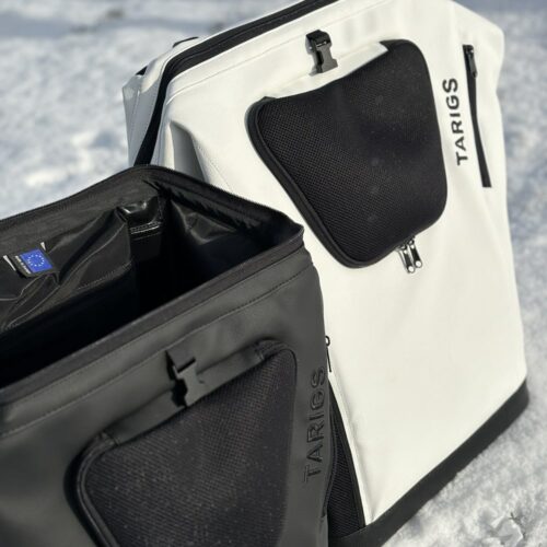 Der MountainRock Backpack - Black (Vegan Leather) & MountainRock Backpack - White (Vegan Leather) stehen im Schnee. Der Hunderucksack in Schwarz ist oben offen.